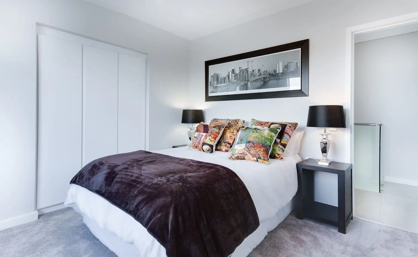 A warm white wall with a brass hanging lamp and woven tapestry
